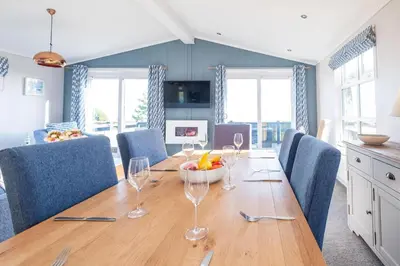 a dining room with a wooden table with wine glasses at Sea Breeze - Aldeburgh Coastal Cottages in Sizewell