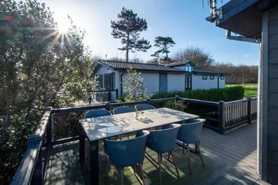 a patio with a table and chairs on a deck at Sea Breeze - Aldeburgh Coastal Cottages in Sizewell