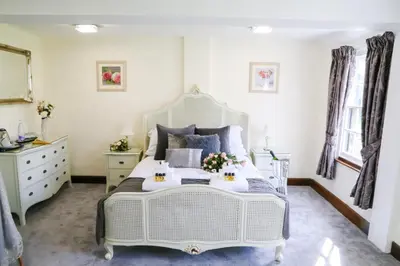 a bedroom with a white bed with two serving tables at Little Easton Manor in Great Easton