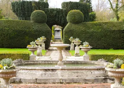 a garden with a fountain and some bushes at Little Easton Manor in Great Easton