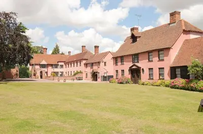 a large pink house with a large grass yard at Little Easton Manor in Great Easton