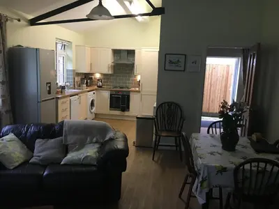 a living room with a couch and a table and a kitchen at Lemondrop Cottage in Southburgh