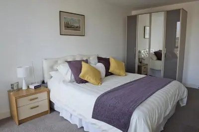 a bedroom with a large bed with purple and yellow pillows at Toothbrush Apartments - Ipswich Waterfront South - Avalon Court in Ipswich