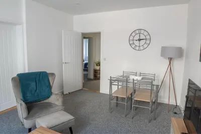 a living room with a chair and a table and a clock at Toothbrush Apartments - Central Ipswich - Fore St in Ipswich