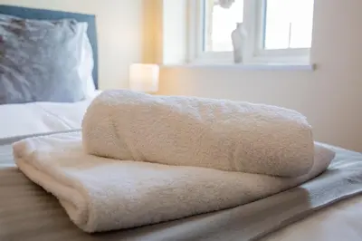 a white towel sitting on top of a bed at 2 Bedroom Penthouse, Clockhouse, Hoddessdon in Hoddesdon