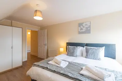 a bedroom with a large white bed with pillows at 2 Bedroom Penthouse, Clockhouse, Hoddessdon in Hoddesdon