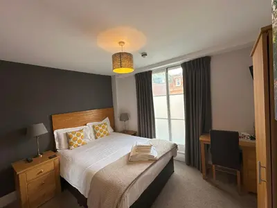 a bedroom with a bed and a desk and a window at The North Hill Hotel, Colchester in Colchester