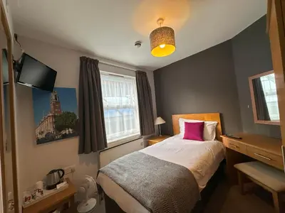 a bedroom with a bed with a pink pillow at The North Hill Hotel, Colchester in Colchester