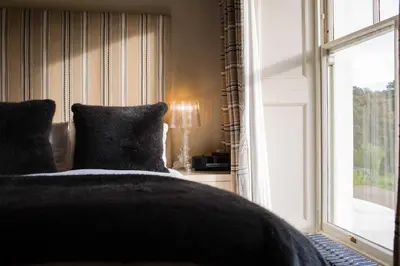 a bed with a black blanket next to a window at Milsoms Kesgrave Hall in Ipswich