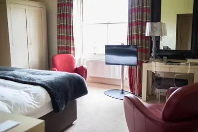 a bedroom with a bed and a desk and a television at Milsoms Kesgrave Hall in Ipswich