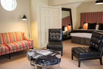 a hotel room with a bed and a couch and a chair at Milsoms Kesgrave Hall in Ipswich