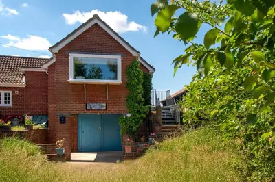 a brick house with a blue garage at 2 Bed in Snape oc-sfvin in Snape
