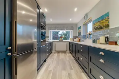 a kitchen with blue cabinets and a stainless steel refrigerator at 2 Bed in Snape oc-sfvin in Snape