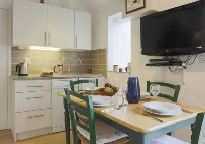 a kitchen with a table with chairs and a television at High Tide in Aldeburgh