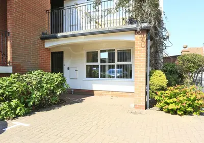a brick house with a balcony and a brick driveway at 2 Coastguard Court in Aldeburgh