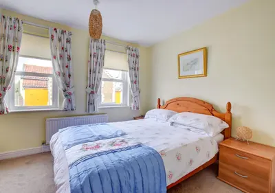 a bedroom with a bed and two windows at 2 Coastguard Court in Aldeburgh