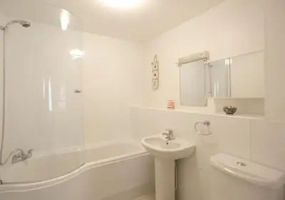 a white bathroom with a sink and a toilet and a shower at 2 Coastguard Court in Aldeburgh