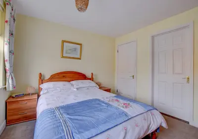 a bedroom with a bed with a blue comforter at 2 Coastguard Court in Aldeburgh