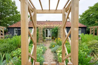 a garden with a pergola in front of a house at 1 Bed in Wilby oc-wlo in Wilby