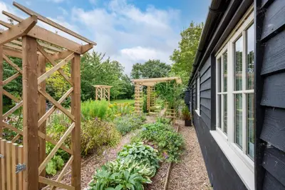 a garden with a wooden trellis next to a house at 1 Bed in Wilby oc-wlo in Wilby