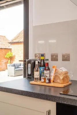 a cutting board with alcohol and bread on a kitchen counter at 1 Bed in Halesworth oc-bbb in Bramfield