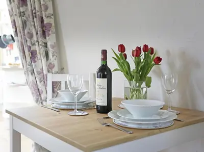 a table with a bottle of wine and a vase of flowers at 1 Bed in Wickham Market oc-samp in Wickham Market