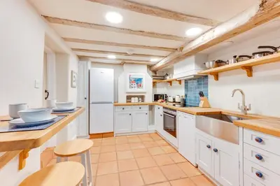 a large kitchen with white cabinets and wooden ceilings at 1 Bed in Ipswich oc-spha in Harkstead