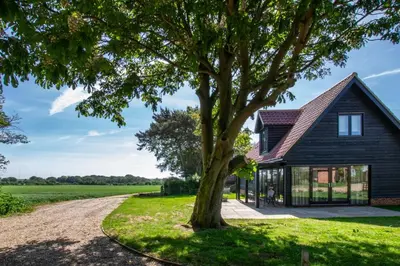 a house with a tree next to a dirt road at 1 Bed in Sudbourne oc-tgs in Sudbourne