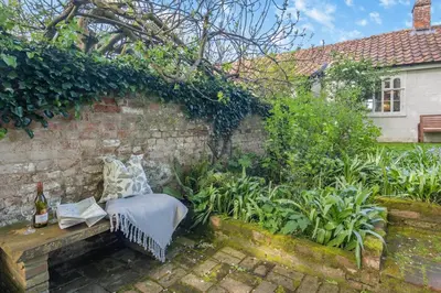 a garden with a bench next to a brick wall at 1 Bed in Great Bealings oc-sfgar in Bealings