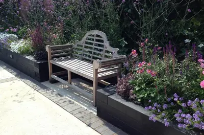 a wooden bench sitting in a garden with flowers at 1 Bed in Woodbridge oc-stabu in Ufford