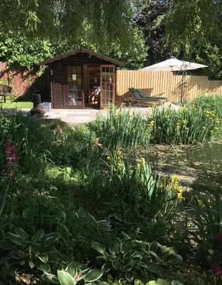 a garden with a wooden building in the background at 1 Bed in Woodbridge oc-stabu in Ufford