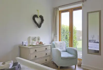 a bedroom with a dresser and a chair and a heart on the wall at 1 Bed in Saxmundham oc-stab in Friston