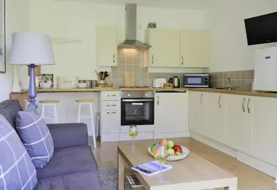 a kitchen with a couch and a table with a bowl of fruit at 1 Bed in Saxmundham oc-stab in Friston