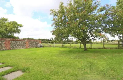 a tree in a field next to a fence at 1 Bed in Saxmundham oc-stab in Friston