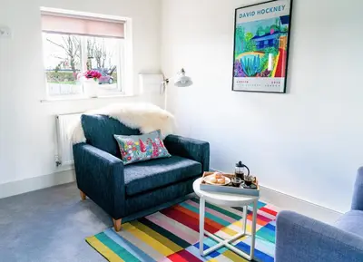 a living room with a blue chair and a table at Elm Cottage at Gravel Farm in Stretham
