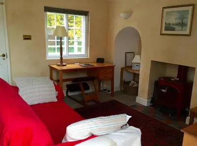 a living room with a red couch and a desk at The Old Post Office, Hilton in Huntingdon