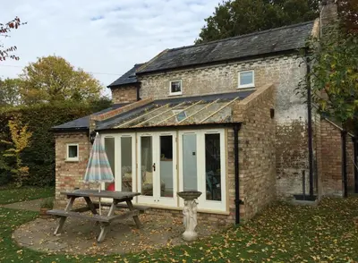 a small brick building with a large window and a picnic table at The Old Post Office, Hilton in Huntingdon