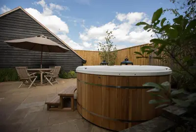 a wooden hot tub with a table and an umbrella at Channels Retreat in Chelmsford