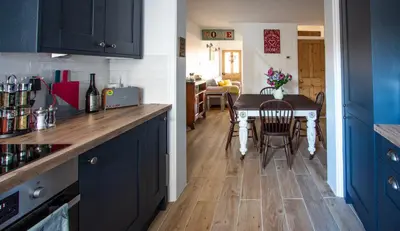 a kitchen with blue cabinets and a table with chairs at Stylish Town Centre House with Garden and Parking Opposite in Bury Saint Edmunds