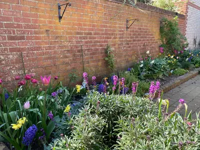 a garden with flowers in front of a brick wall at Stylish Town Centre House with Garden and Parking Opposite in Bury Saint Edmunds