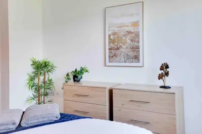 a bedroom with a bed and a dresser with two plants at Niche Parkview Apartments in Brentwood