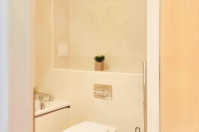 a bathroom with a toilet and a plant on a tub at Niche Parkview Apartments in Brentwood