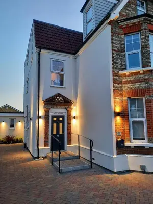 a white building with a black door and a staircase at Viva Guest House in Clacton-on-Sea
