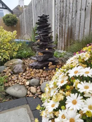 a garden with a stone fountain and flowers in front of a fence at Viva Guest House in Clacton-on-Sea