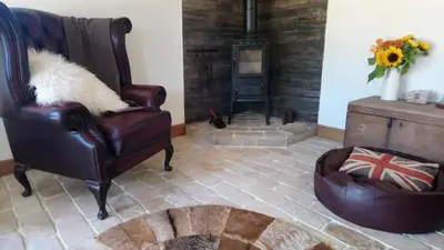 a living room with a chair and a wood stove at The Dovecote - unique self-contained 1bed renovated barn in Saffron Walden