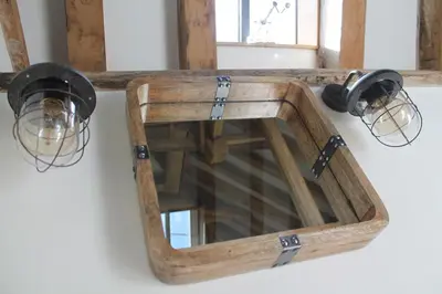 a wooden mirror hanging on a wall with lights at The Dovecote - unique self-contained 1bed renovated barn in Saffron Walden