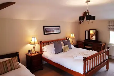a bedroom with a large bed and two lamps at The Coach House at Lodge Farm with Hot Tub in Hilgay