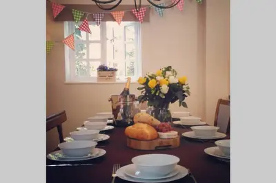 a table with plates and bowls and a vase of flowers at The Coach House at Lodge Farm with Hot Tub in Hilgay