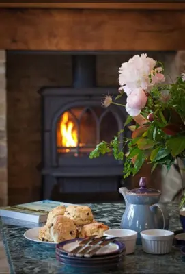 a table with a plate of cookies in front of a fireplace at The Coach House at Lodge Farm with Hot Tub in Hilgay