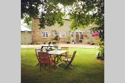 a table and chairs in the yard of a house at The Coach House at Lodge Farm with Hot Tub in Hilgay